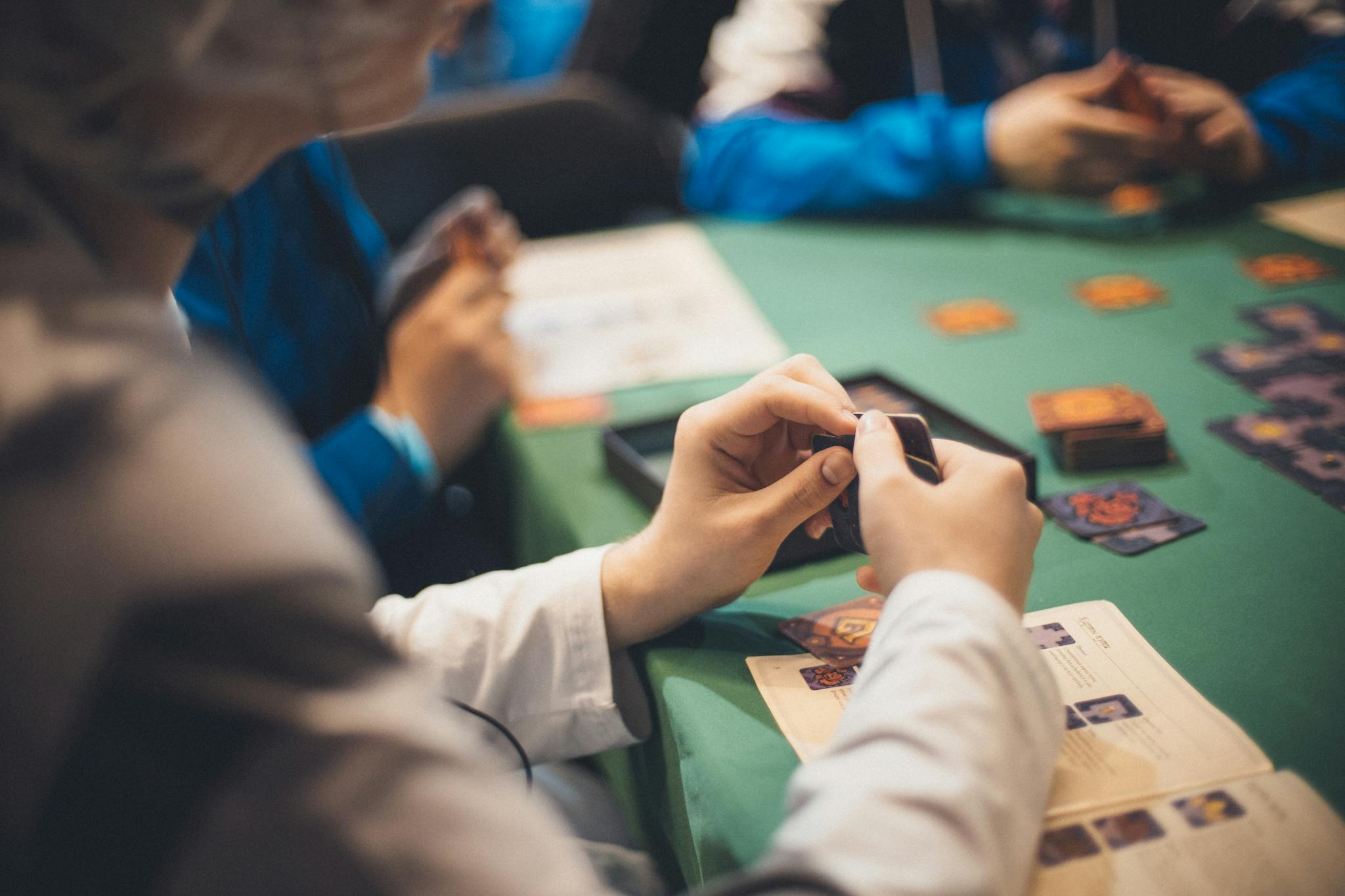 A group of adults engaged in a fun card game tournament with strategy guides on the table.